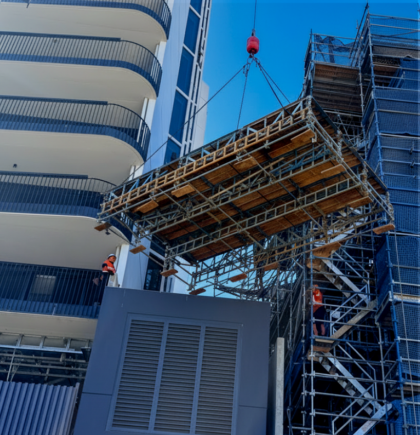 Crane lifting a modular scaffold platform into place on a commercial construction project