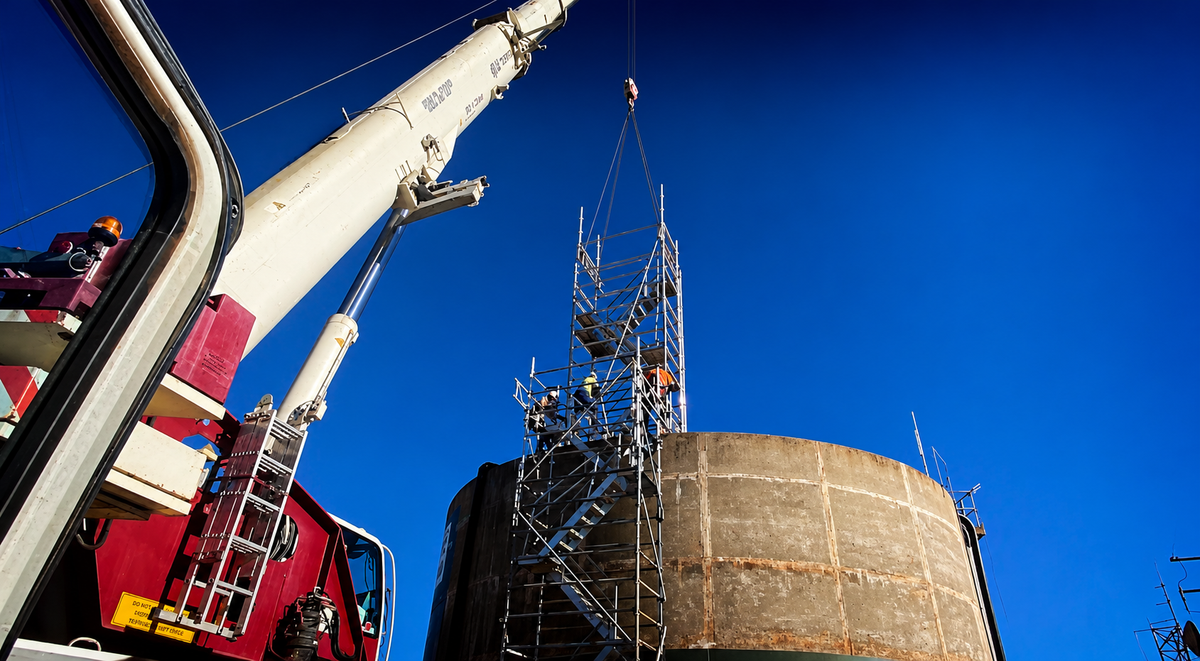 Scaffold installation by crane around a concrete tank on an industrial site in regional NSW